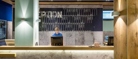 A reception desk with a modern design, a laptop, and a handbag on the counter.