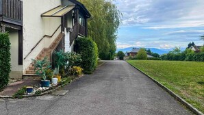 En bostadsgata med ett hus som har en veranda, en trappa och en uppfart.