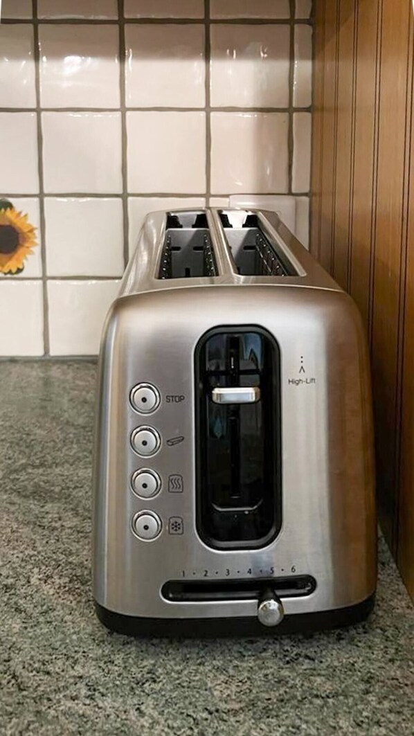 A stainless steel toaster with a high-lift mechanism, four control buttons, and a dial for setting the toasting level.