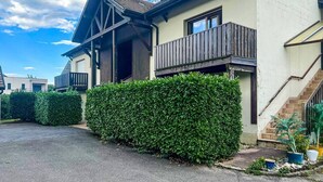 En bostadsbyggnad med ett sluttande tak, en balkong och en trappa som leder till entrén.