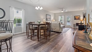 A spacious living area with a dining table and chairs, a sofa, and a piano. - Willow Bend #1411 Nice Condo! (North Myrtle Beach)