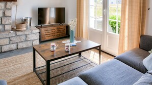 Una sala de estar con chimenea de piedra, un televisor, una mesa de centro con tazas y un sofá.