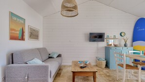A living room with a grey sofa, a wooden coffee table, a TV, and a surfboard.