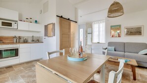 A modern kitchen with white cabinets, a wooden countertop, and a dining area with a table and chairs.