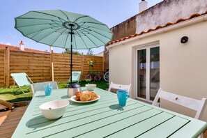 Eine Terrasse mit einem Tisch, gedeckt für das Frühstück, darunter Croissants, eine Schüssel und eine Tasse.