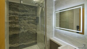 A modern bathroom with a glass-enclosed shower, a marble wall, and a large mirror above a sink. - Marina Walk, New Luxury Coastal Apartment in The English Riviera (Torquay)