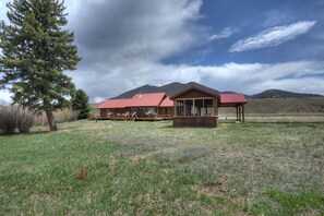 Ein Chalet mit rotem Dach, großen Fenstern und einer überdachten Veranda.