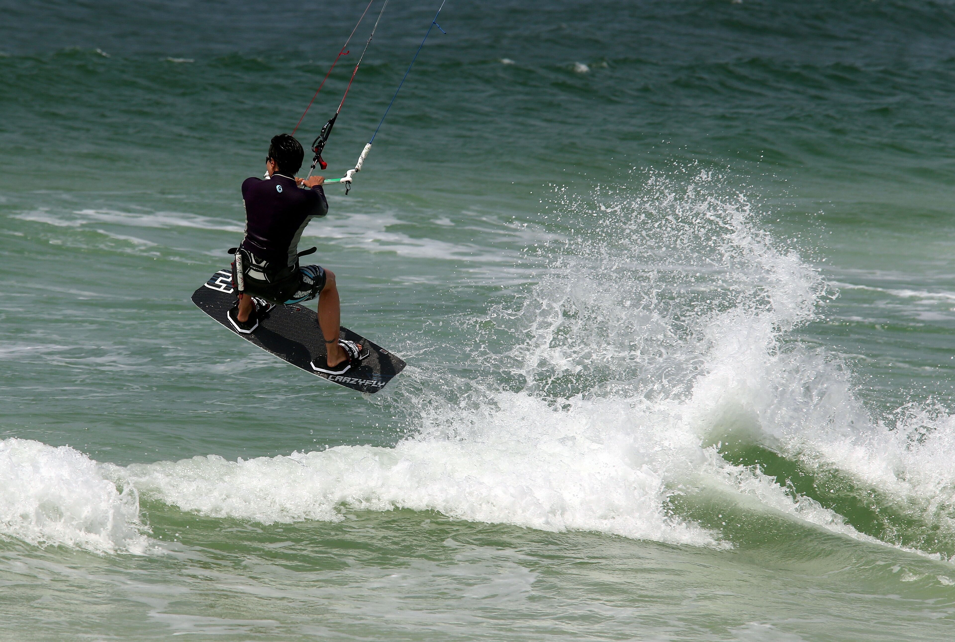 Eine Person kitesurft über dem Wasser.