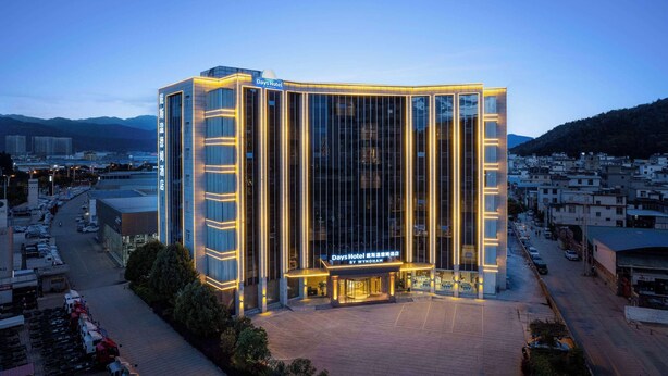 Un hôtel moderne, avec une enseigne bien visible, de grandes fenêtres et une entrée bien éclairée.