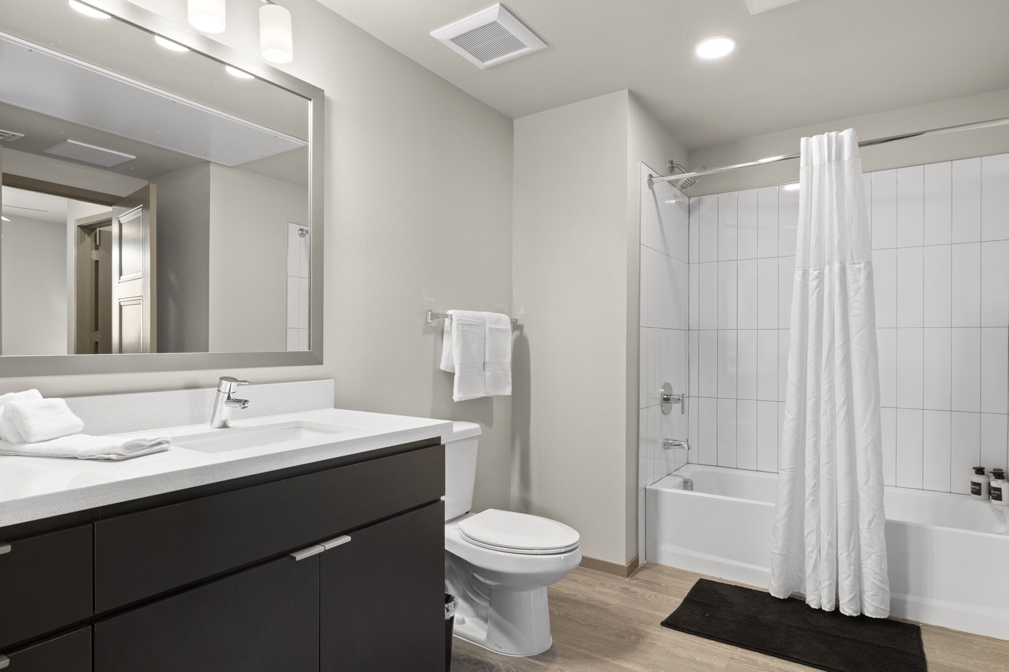 Een moderne badkamer met een grote spiegel, een witte wastafel, toilet en douche.