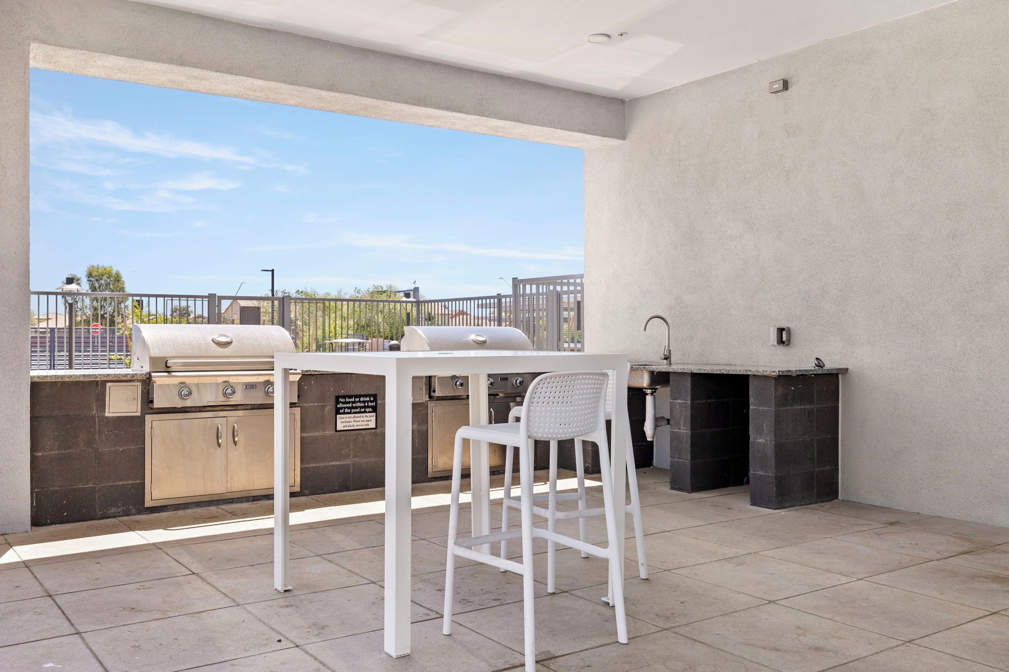 An outdoor patio with a grill, a table, and a chair.