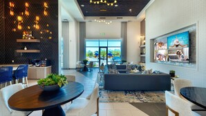 Un hall d’hôtel moderne avec un mur à motifs sombres, une grande fenêtre et un coin salon comprenant un canapé et des fauteuils.