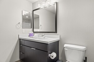 Un baño moderno con un lavabo blanco, mueble oscuro y un inodoro.