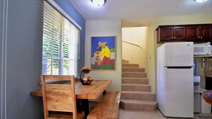Une cuisine avec une table en bois, un banc, un réfrigérateur et un four à micro-ondes.