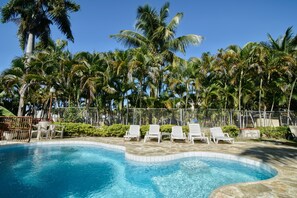 A swimming pool with lounge chairs and palm trees. - Charming Villa in Sosua (Sosua)