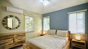 Une chambre à coucher comprenant un lit, une commode en bois et deux tables de chevet avec des lampes.