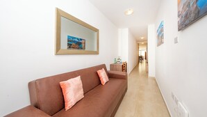 Un salon moderne avec un canapé marron, une petite table d’appoint et un tableau encadré accroché au mur.
