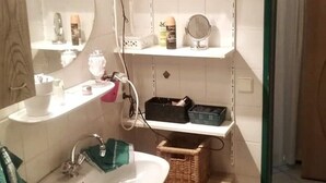 A bathroom with a sink, mirror, shelves, and a door. - Komfortable Wohnung Zentral zur City(5km) Eifel(10km)
Belgien(2km)Holland(12km) (Aachen)