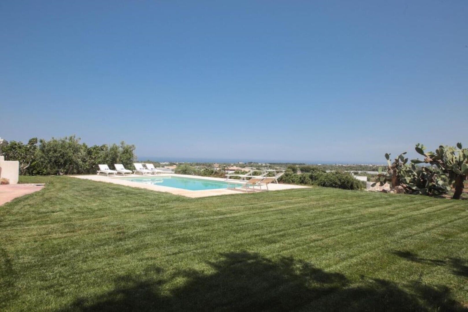 A well-maintained lawn with a swimming pool and lounge chairs.