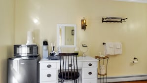 A bathroom with a sink, mirror, towel rack, and a coffee machine. - The Thistle Inn (Boothbay Harbor)