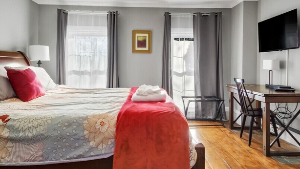 A hotel room with a bed, a desk, a chair, a television, and a picture on the wall. - The Thistle Inn (Boothbay Harbor)