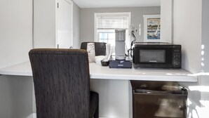 A compact kitchenette with a microwave, coffee maker, and a small trash bin. - The Thistle Inn (Boothbay Harbor)
