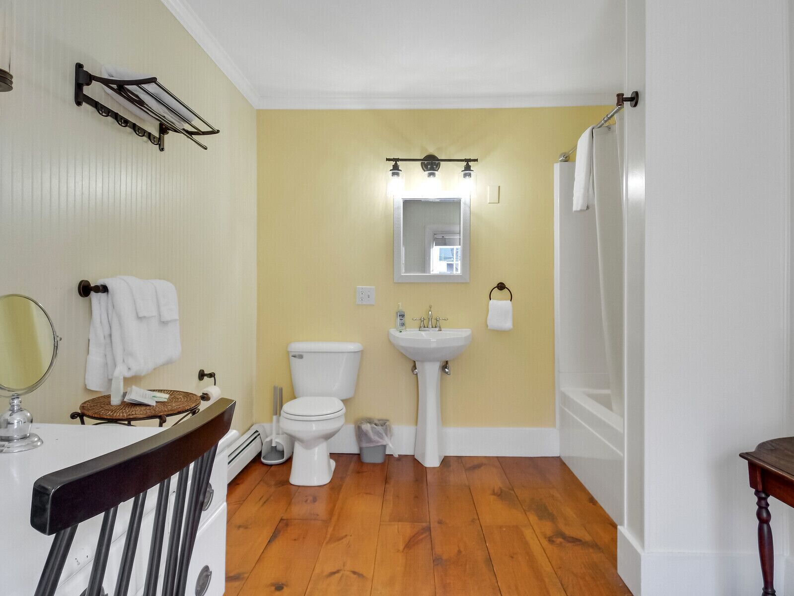 A bathroom with a toilet, sink, and mirror.