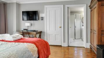 Una habitación de hotel con cama, escritorio, televisión y armario.