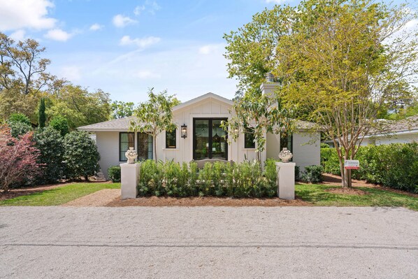 A two-story house with a front porch, a driveway, and a well-maintained garden. - Quaint Cottage near the village with pool (St Simons Island)