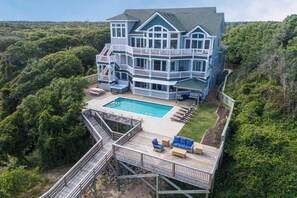 A large, multi-story house with a pool, deck, and outdoor furniture. - Premier Soundfront Dog Friendly w/ Pool, Hot Tub, Elevator, Theater & Game Rooms (Buxton)