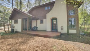 Een modern huis met een overdekte veranda, een grote schoorsteen en een voordeur met een raam erboven.