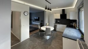 A modern kitchen with a dining area, a built-in oven, and a large window. - Modernes Reihenhaus mit Garten (Magdeburg)