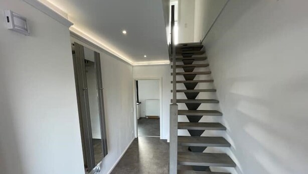 A modern staircase with a minimalist design, leading to a room with a neutral color scheme and a clean, uncluttered space. - Modernes Reihenhaus mit Garten (Magdeburg)