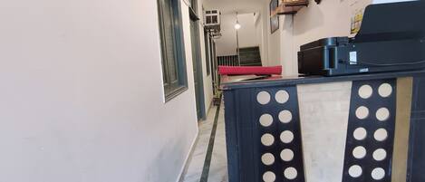 A narrow hallway with a reception desk featuring circular cutouts, air conditioning units, and a red mat on the floor.