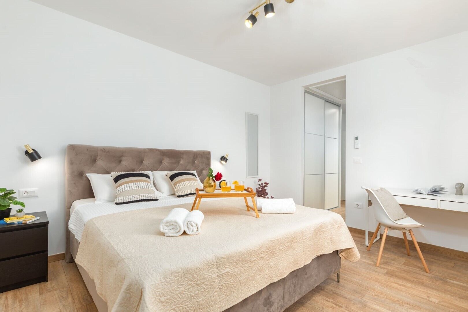 Una camera da letto moderna con un letto grande, comodini, una scrivania e una sedia.