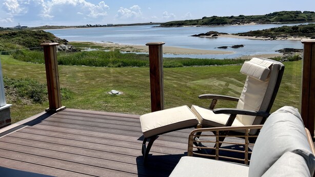 Terraza con una silla y una mesa con vista a la playa y al agua.