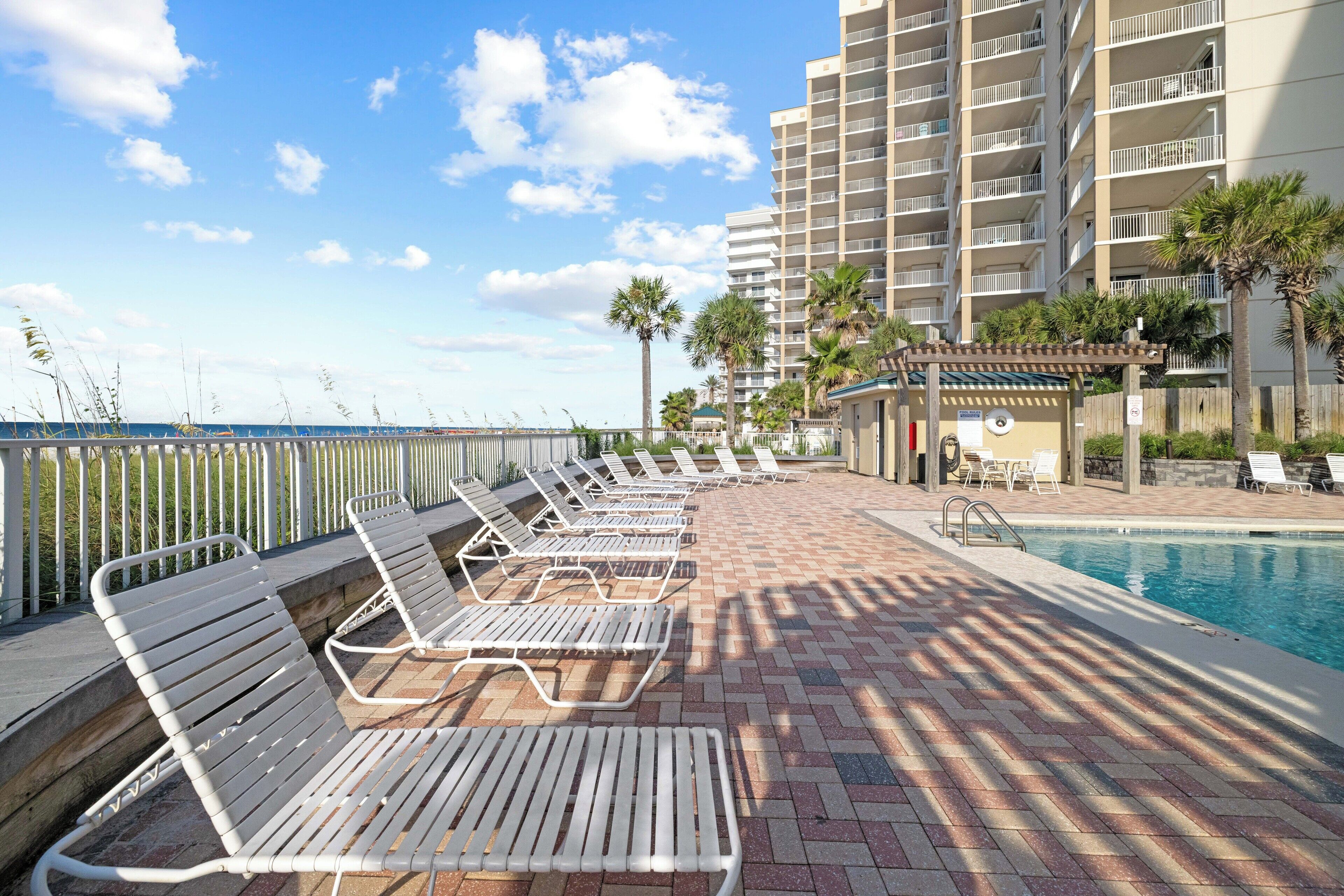 A poolside area with lounge chairs, a small pool, and a building with balconies.