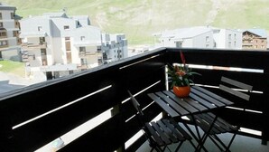 A balcony with a view of a mountainous landscape, a potted plant, and a wooden bench. - 100m from resort center, 4th floor, balcony, tv, ski locker, 24m², Tignes (Tignes)