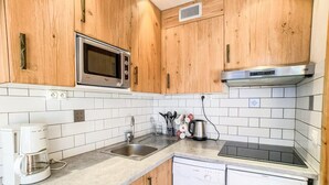 A compact kitchen with wooden cabinets, a microwave, a coffee maker, a dishwasher, and a gas stove. - 100m from resort center, 4th floor, balcony, tv, ski locker, 24m², Tignes (Tignes)