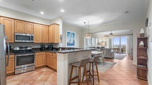 Una cocina moderna con armarios de madera, electrodomésticos de acero inoxidable y una isla grande con taburetes de bar.