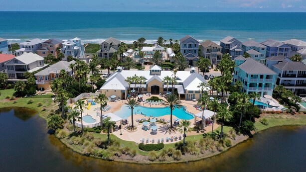 Un resort con piscina central, varias edificaciones y vista al océano.