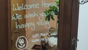 A wooden door with a glass panel displaying a welcome message in Spanish. - Piso As Rodas (Vilanova de Arousa)
