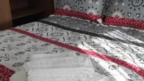 A bed with patterned bedding and a folded white towel. - Piso As Rodas (Vilanova de Arousa)