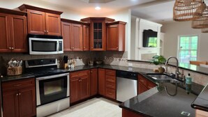 A modern kitchen with wooden cabinets, stainless steel appliances, and a black countertop. - Creekside Orchards townhome in the heart of Chambersburg! (Chambersburg)