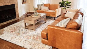 A living room with a fireplace, a sofa, a coffee table, and a ceiling fan. - Creekside Orchards townhome in the heart of Chambersburg! (Chambersburg)
