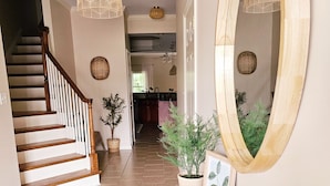 A hallway with a wooden staircase, a mirror, a wooden table with decorative items, and a potted plant. - Creekside Orchards townhome in the heart of Chambersburg! (Chambersburg)