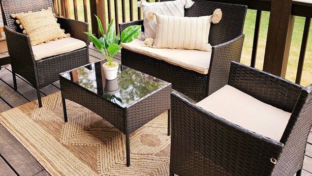A wooden deck with wicker furniture, including chairs and a sofa with cushions, and a glass coffee table with a potted plant. - Creekside Orchards townhome in the heart of Chambersburg! (Chambersburg)