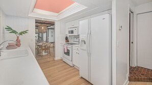 Una cucina moderna con elettrodomestici bianchi, una zona pranzo con tavolo in legno e un lucernario.