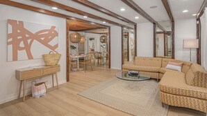 Un ampio soggiorno con un divano grande, un'area pranzo con sedie e un soffitto in legno.