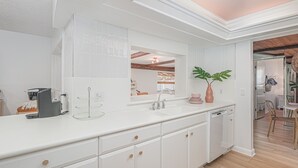 Una cucina moderna con mobili bianchi, un grande specchio e una macchina per caffè.